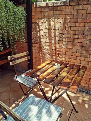 a wooden bench and two chairs in front of a brick wall at TAVEE Guesthouse in Bangkok