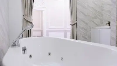 a white tub in a bathroom with a window at VARIMANTRA HOTEL in Nakhon Pathom