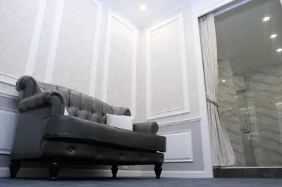 a black leather couch in a room with a shower at VARIMANTRA HOTEL in Nakhon Pathom