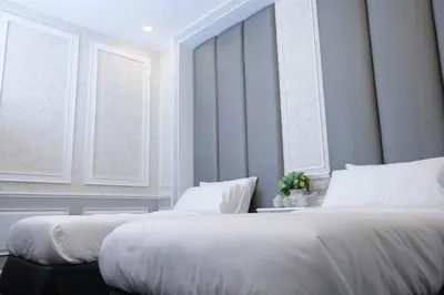 a bedroom with two beds and two windows at VARIMANTRA HOTEL in Nakhon Pathom