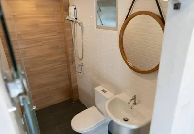 a bathroom with a toilet and a sink and a mirror at Malades House in Bangkok