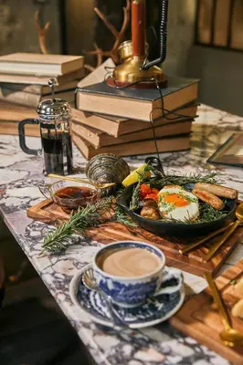 a table with a plate of food and a cup of coffee at The Mustang Blu in Bangkok