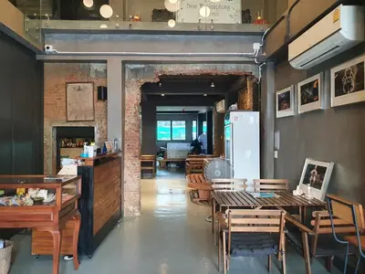 a dining room with tables and chairs and a refrigerator at Baan Wualamphong บ้านวัวลำพอง in Bangkok