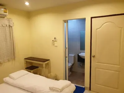 a small bathroom with a bed and a toilet at Papermoon Guesthouse in Bangkok
