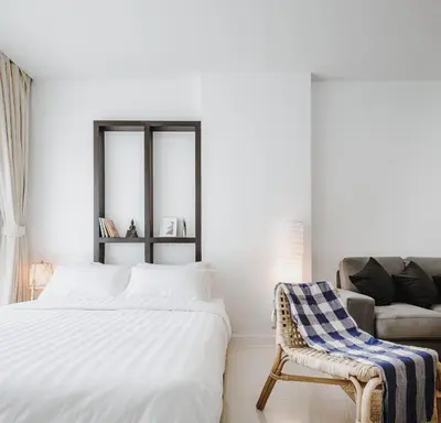a white bedroom with a bed and a chair at Siamplaengna Residence in Bangkok