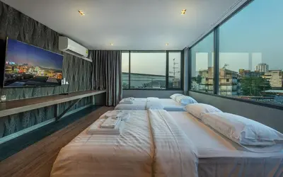 a room with three beds and a flat screen tv at Happy Station Bangkok in Bangkok