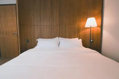 a large white bed in a room with a lamp at 41Cafetel in Bangkok