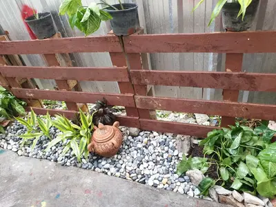 a fence with a pot on the ground next to a garden at TP home in Bangkok