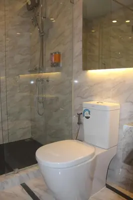a bathroom with a white toilet and a shower at H-District Boutique Poshotel in Bangkok