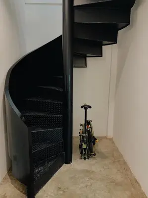 a black spiral staircase in a white room at Marlowe-Tony's home in Bangkok