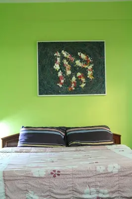 a bedroom with a bed with a painting on the wall at Swan inn 2 Nana in Bangkok