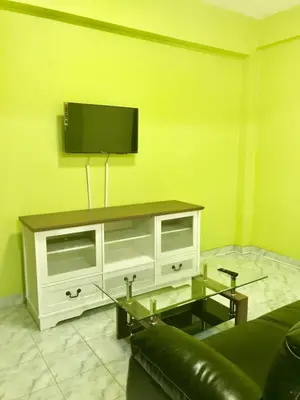 a living room with a tv on a yellow wall at Swan inn 2 Nana in Bangkok