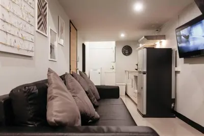 a living room with a black leather couch and a television at S1 Large Duplex Silom 3 Beds, Full Kitchen WIFI in Bangkok