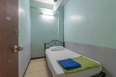 a small room with a small bed with a blue blanket at 7 Holder Guesthouse in Bangkok