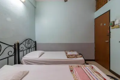 two beds in a small room with a door at 7 Holder Guesthouse in Bangkok