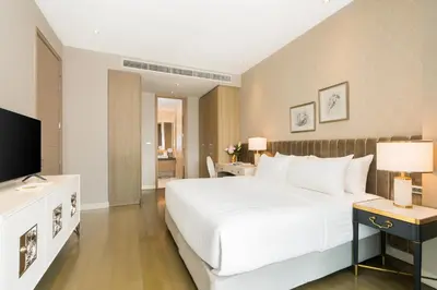 a bedroom with a large white bed and a television at Magnolias Ratchadamri Boulevard Serviced Residences in Bangkok