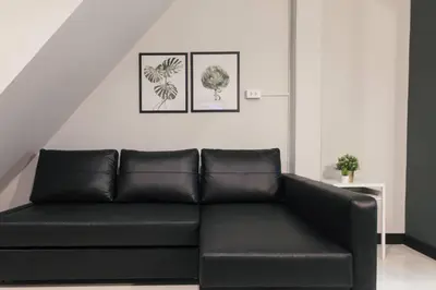 a black couch in a living room with two pictures on the wall at S2 Silom Large room 4-6 guests Full kitchen WIFI in Bangkok