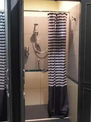 a bathroom with a shower with black and white curtains at Chomm House in Bangkok