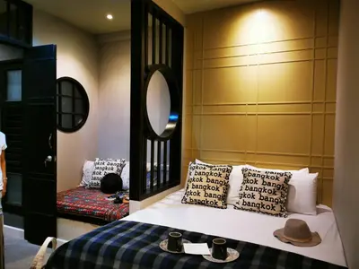 a bedroom with a bed with pillows and a mirror at Chomm House in Bangkok
