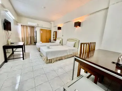 a bedroom with two beds and a table and a desk at Win Mansion in Bangkok