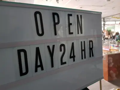 a sign for a grocery store with the words open dancing at Win Mansion in Bangkok