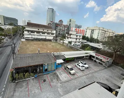 a building with two cars parked in a parking lot at Win Mansion in Bangkok