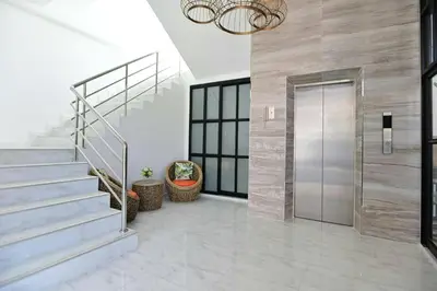 a lobby with a staircase and a glass door at Parvena Ratchada in Bangkok