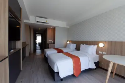 a hotel room with two beds and a table at Marsi Hotel @ Bangchak in Bangkok