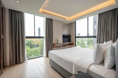a bedroom with a large bed and large windows at Walton Suites Sukhumvit in Bangkok