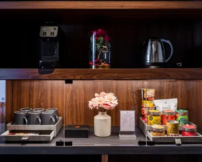 a shelf with food and a vase with flowers on it at Walton Suites Sukhumvit in Bangkok