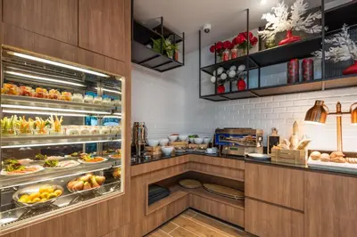a kitchen with a display case filled with food at Maitria Hotel Rama 9 Bangkok - A Chatrium Collection in Bangkok