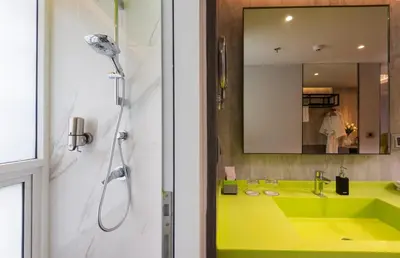 a bathroom with a yellow sink and a shower at Maitria Hotel Rama 9 Bangkok - A Chatrium Collection in Bangkok