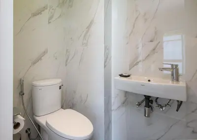 a white bathroom with a toilet and a sink at Maitria Hotel Rama 9 Bangkok - A Chatrium Collection in Bangkok