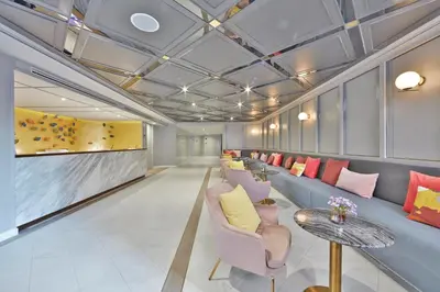 a waiting room with couches and chairs and a table at The Quarter Ploenchit by UHG in Bangkok