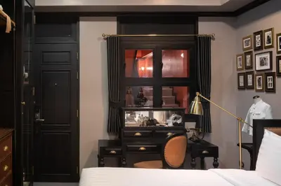a bedroom with a bed and a dresser and a mirror at DE Phanakron Boutique Hotel in Bangkok
