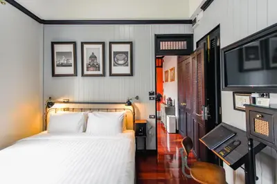 a bedroom with a bed and a flat screen tv at DE Phanakron Boutique Hotel in Bangkok