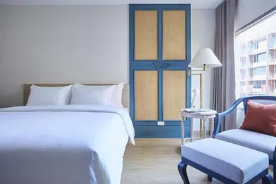 a bedroom with a bed and a chair and a window at 56 Surawong Hotel Bangkok in Bangkok
