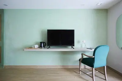 a living room with a chair and a television on a shelf at 56 Surawong Hotel Bangkok in Bangkok
