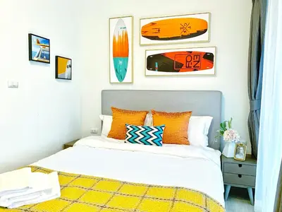 a bedroom with a bed with orange pillows and pictures at Chapter One Eco-Modern Suite (\u66fc\u8c37\u9ad8\u7aef\u9152\u5e97\u516c\u5bd3\uff09 in Bangkok