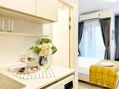 a white room with a bed and a table with flowers at Chapter One Eco-Modern Suite (\u66fc\u8c37\u9ad8\u7aef\u9152\u5e97\u516c\u5bd3\uff09 in Bangkok
