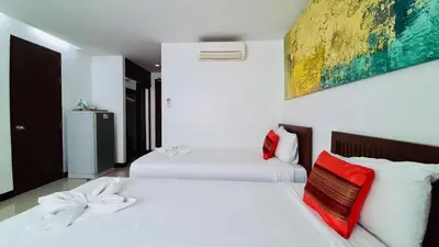 two white beds in a bedroom with a painting on the wall at City Plaza Nana Hotel in Bangkok