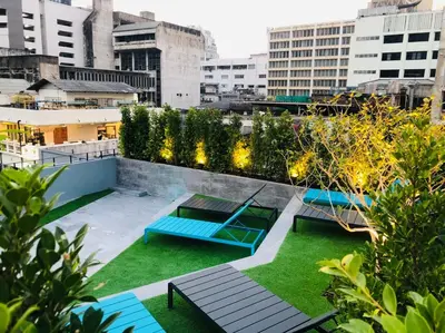 a rooftop garden with blue benches and green grass at The Quarter Silom by UHG in Bangkok