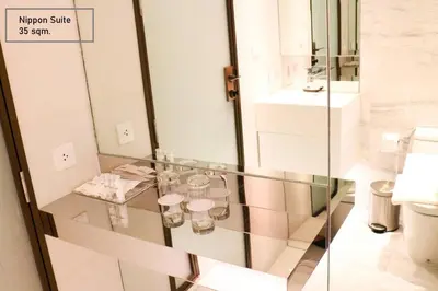 a glass table in a bathroom with a toilet at ashley hotel bkk in Bangkok