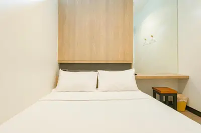 a bedroom with a white bed and a wooden cabinet at T Hostel @ Victory Monument in Bangkok