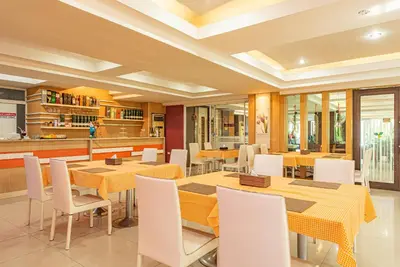 a dining room with yellow tables and white chairs at The Wing Design Hotel in Bangkok