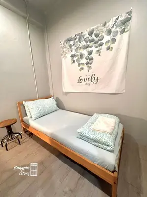 a bed in a room with a sign on the wall at Bangpho Story in Bangkok