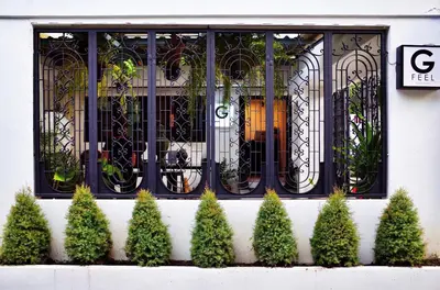 a building with a window and a bunch of plants at Gfeel Hostel in Bangkok