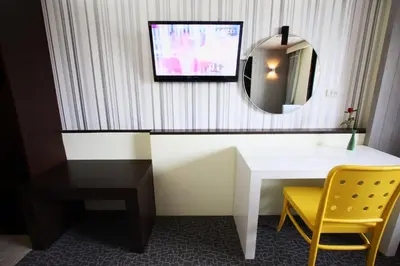 a room with a desk and a mirror and a yellow chair at Royal Delight Hotel in Bangkok