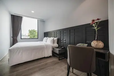a bedroom with a bed and a desk with a chair at VIX Bangkok at Victory Monument in Bangkok