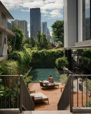 a man sitting in a bath tub in a pool on a balcony at Homm Sukhumvit34 Bangkok in Bangkok